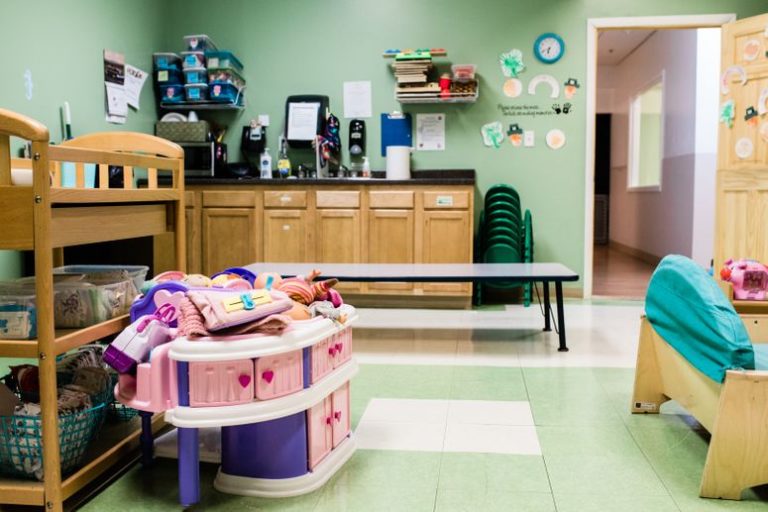 Wooden cabinets and aquamarine sofa with table in the middle without children at a Childcare Serving Branford & Wallingford, CT